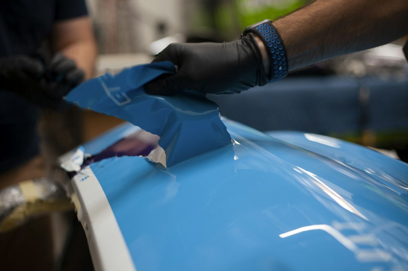 Installer laying Titan film onto a panel with gloved hands and a squeegee